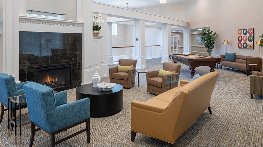 Billiards lounge with fireplace and comfy seating at American House Park Place senior living facility in Warren, MI