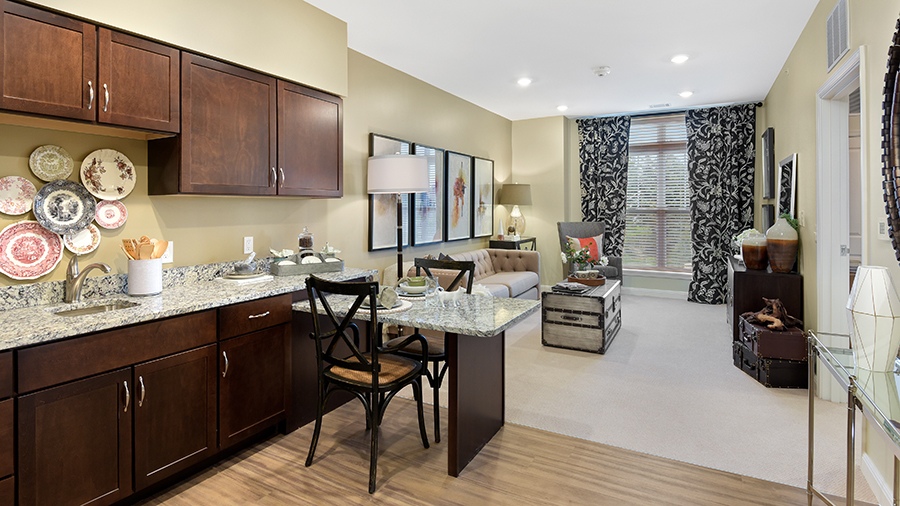 Model apartment kitchen with living room at American House Hampton Village assisted living and memory care facility in Rochester Hills, MI