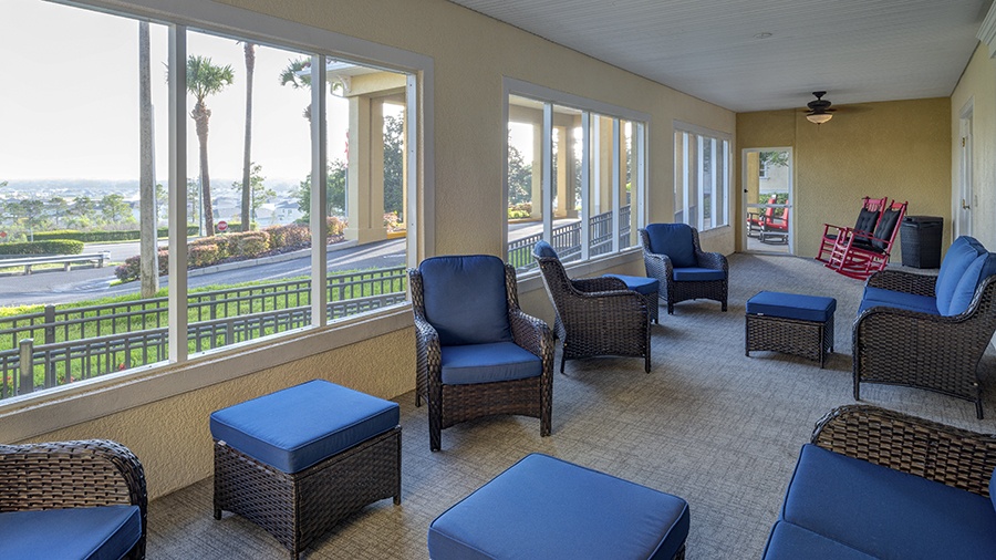 Lanai with comfy seating and rocking chairs at American House assisted living and memory care facility in Zephyrhills, FL