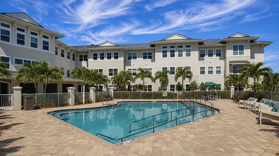 Outdoor pool and lounge chairs at American House Ft. Myers assisted living and memory care facility in Fort Myers, FL