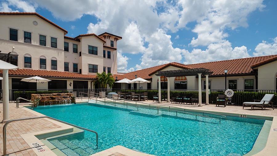 Outdoor pool and deck at American House Coconut Point, a senior living community in Estero, FL