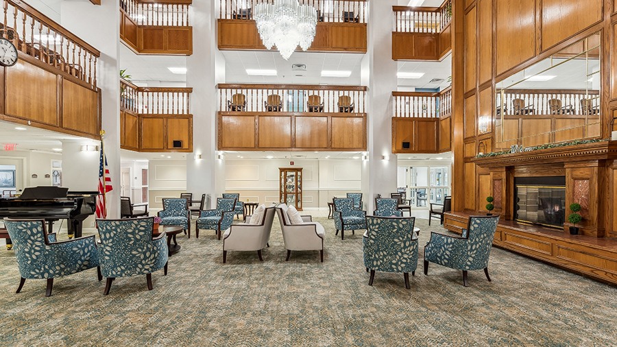 Cozy common area with fireplace and grand piano at American House The Palms senior living community in North Fort Myers, FL