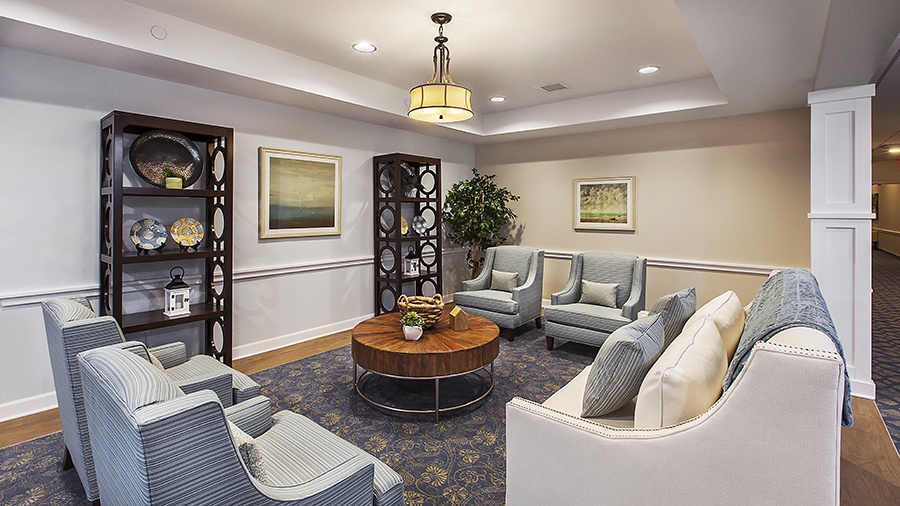 Seating area with sofa and chairs for gathering at American House Lakeshore senior living and memory care facility in Roseville, MI