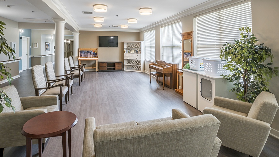 Sitting Room with laundry, tv and piano at American House Bristol Assisted Living and Memory Care Facility in Bristol, TN