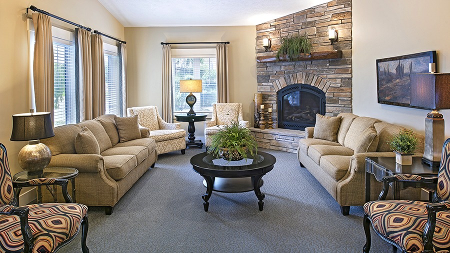 Community gathering room with fireplace and sofas at American House Jenison senior living facility in Jenison, MI