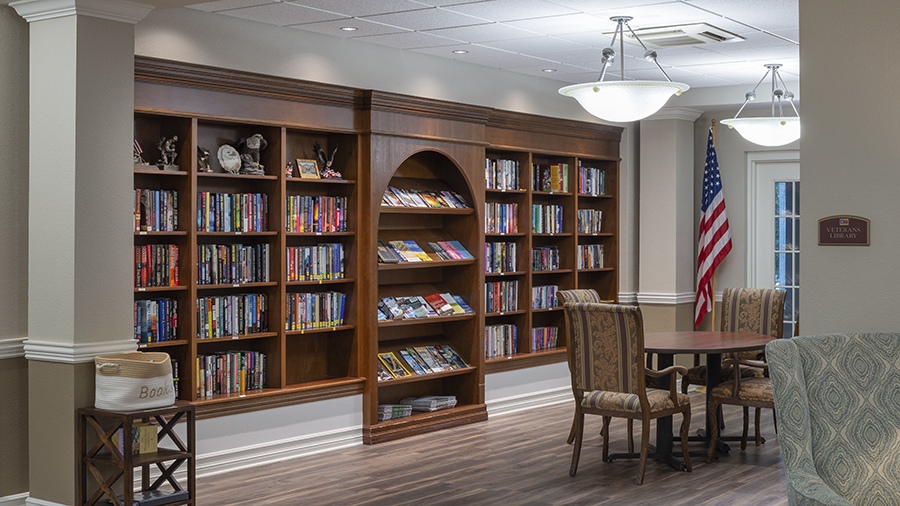 Library with seating and books at American House assisted living and memory care facility in Zephyrhills, FL