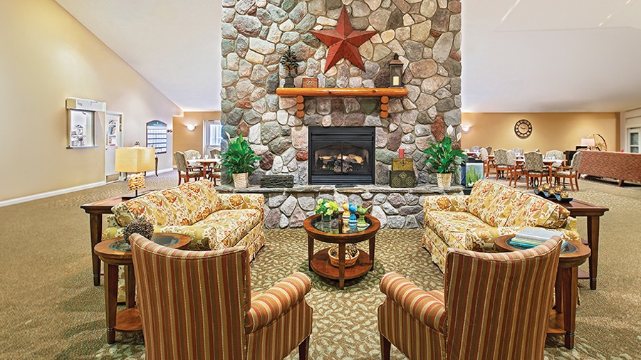 Lobby with fireplace and cozy seating at American House Charlevoix senior and assisted living facility