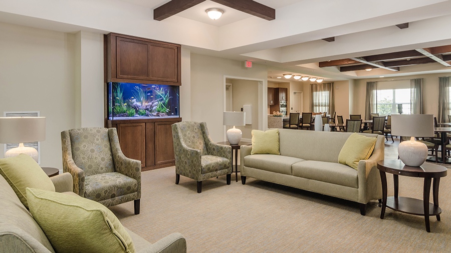 Cozy sitting room with fish tank and sofas at American House Coconut Point, a senior living community in Estero, FL