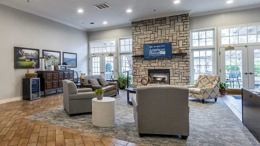 Lobby and cozy sitting area with fireplace and patio at American House Bartlett assisted living facility in Bartlett, TN