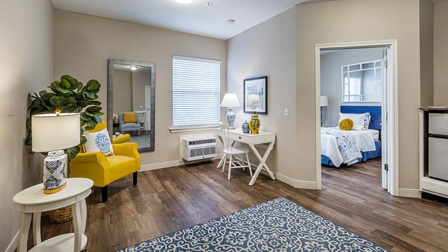 Model living room and bedroom entrance at American House Bartlett assisted living facility in Bartlett, TN