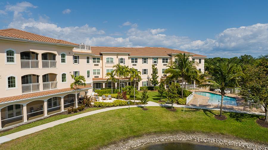 Rear exterior view of pool and building at American House Bonita Springs assisted living and memory care facility