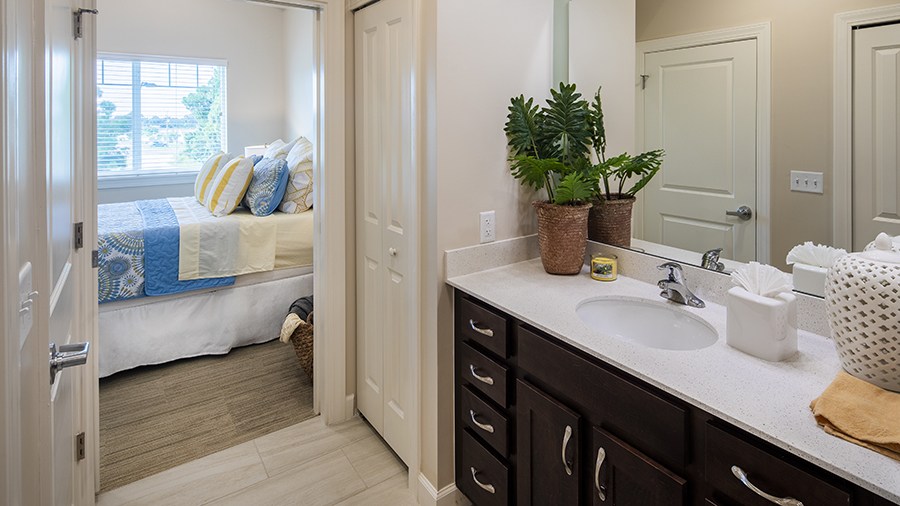 Model bedroom and bathroom at American House St. Petersburg Independent Living, Assisted Living, and Memory Care senior living facility in St. Petersburg, FL