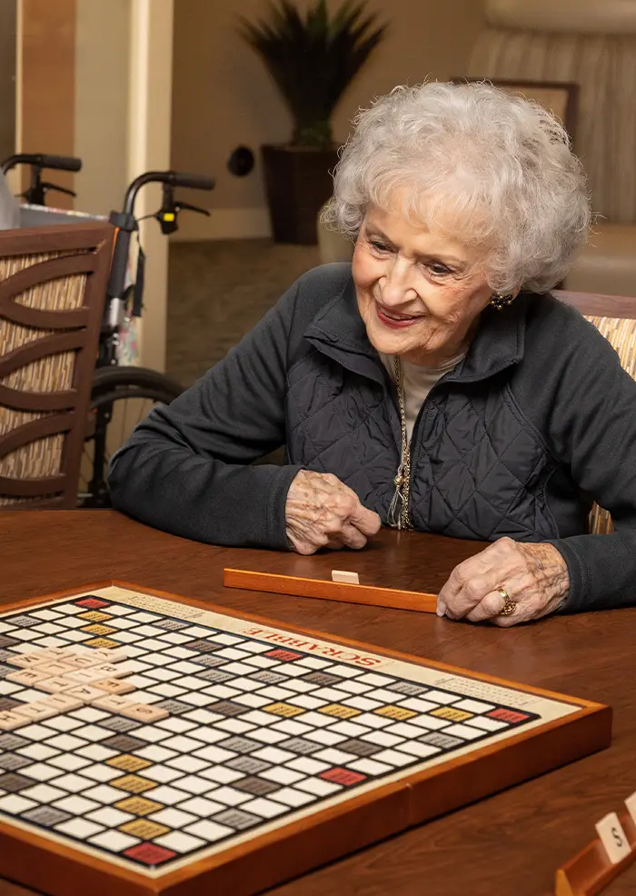 Resident at American House St. Anthony's senior living community playing scrabble